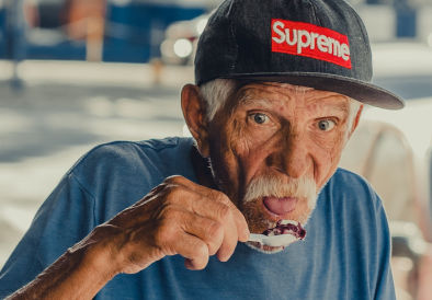 Older man eating chocolate icecream with a plastic spoon